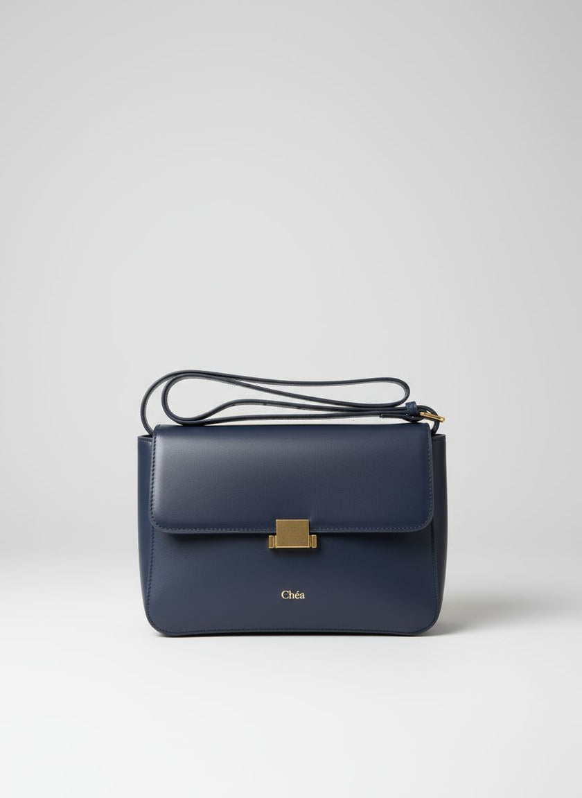 Navy blue handbag with gold clasp on a light gray background